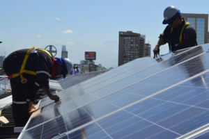Obreros instalando placas solares sobre un tejado.