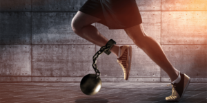 Aldro Energía ofrece una solución que elimina la energía reactiva de las instalaciones elétricas. En la imagen, el efecto negativo de la energía reactiva en las instalaciones eléctricas es representada como un corredor que lleva en uno de sus tobillos un grillete unido a una bola.