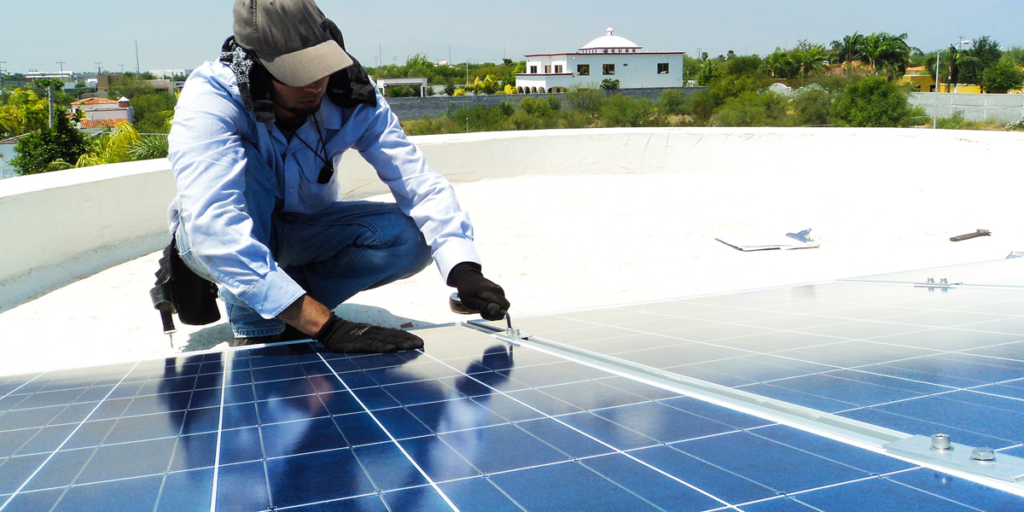 Operario instalando paneles solares sobre la cubierta de un edificio.