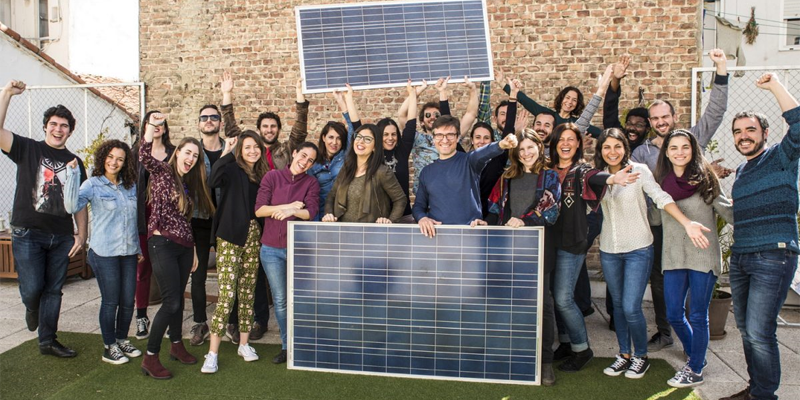 Un grupo de personas posa sosteniendo paneles fotovoltaicos.
