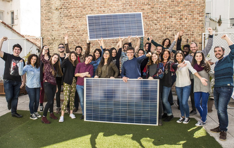 Un grupo de personas posa sosteniendo paneles fotovoltaicos. 
