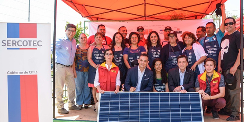 Microempresarios del barrio comercial Ictinos de Chile posan bajo una carpa junto a uno de los 14 paneles fotovoltaicos que serán instalados en sus locales.