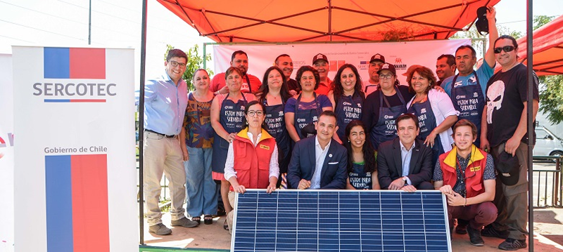 Microempresarios del barrio comercial Ictinos de Chile posan bajo una carpa junto a uno de los 14 paneles fotovoltaicos que serán instalados en sus locales. 