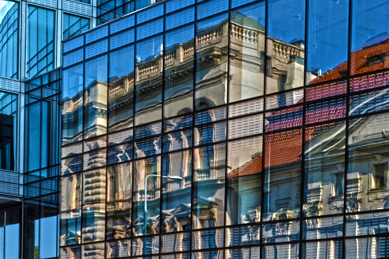 Edificio moderno en cuya fachada se ve reflejada la fachada de un edificio antiguo.