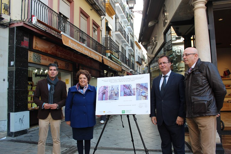 Personalidades del Ayuntamiento de Sevilla posan ante una calle del Casco Antiguo junto a un panel informativo sobre las obras de renovación del alumbrado público. 