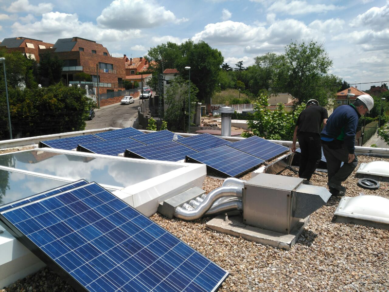Profesionales instalando paneles fotovoltaicos sobre la cubierta de un edificio. 