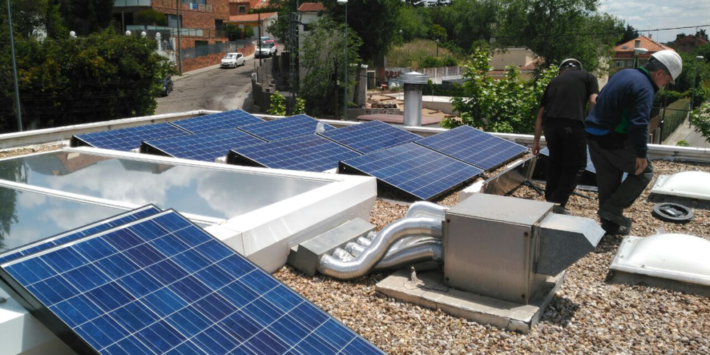 Profesionales instalando paneles fotovoltaicos sobre la cubierta de un edificio.