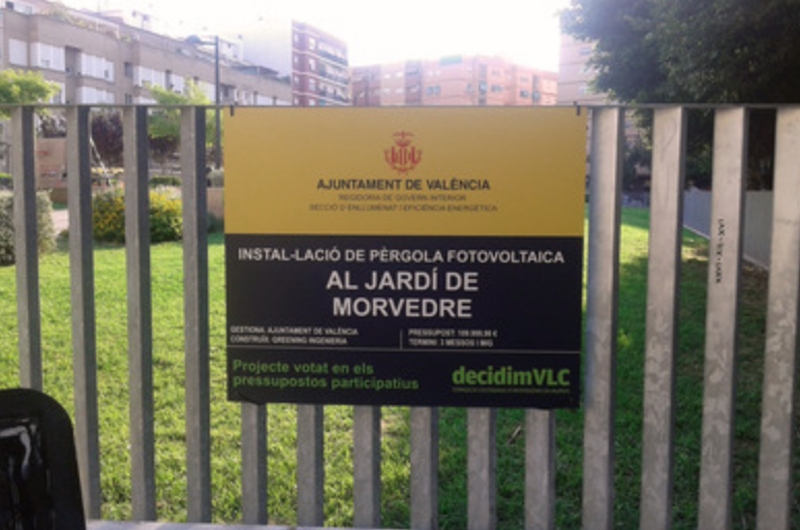 Cartel que anuncia el inicio de las obras para instalar pérgolas fotovoltaicas en el Jardín Morvedre de Valencia. 