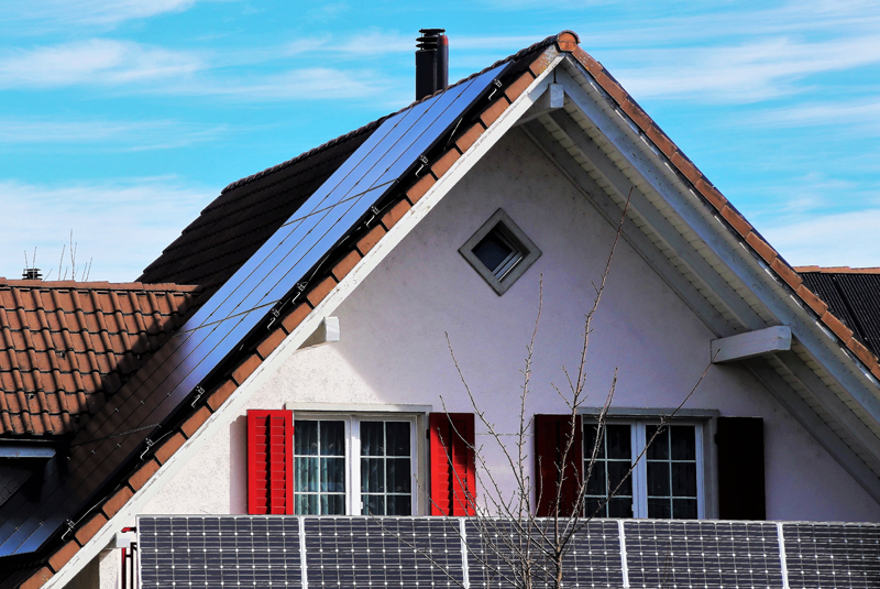 Vivienda con placas fotovoltaicas en balcones y placas de energía solar térmica sobre el tejado inclinado. 