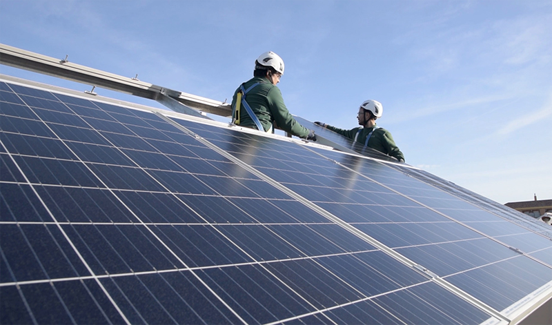 Dos instaladores colocan placas solares en una planta de generación de energía fotovoltaica.