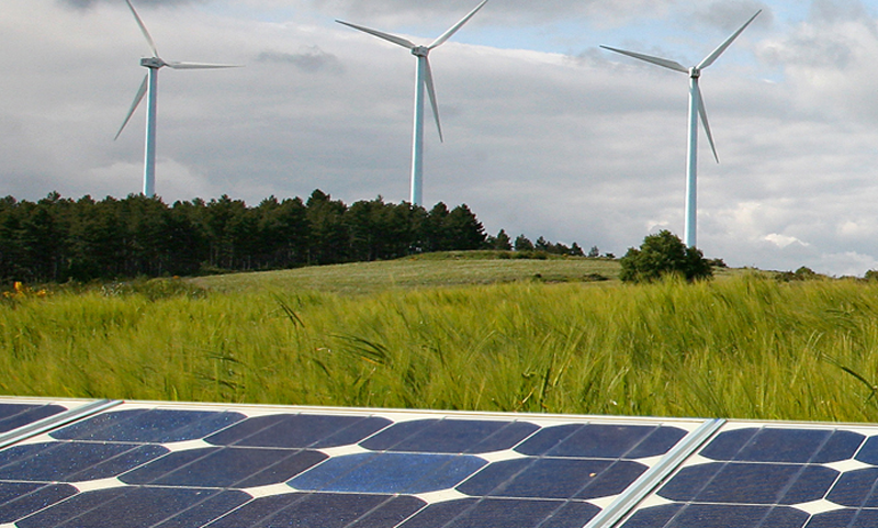 Paneles solares y molinos de viento en un campo, energías renovables.