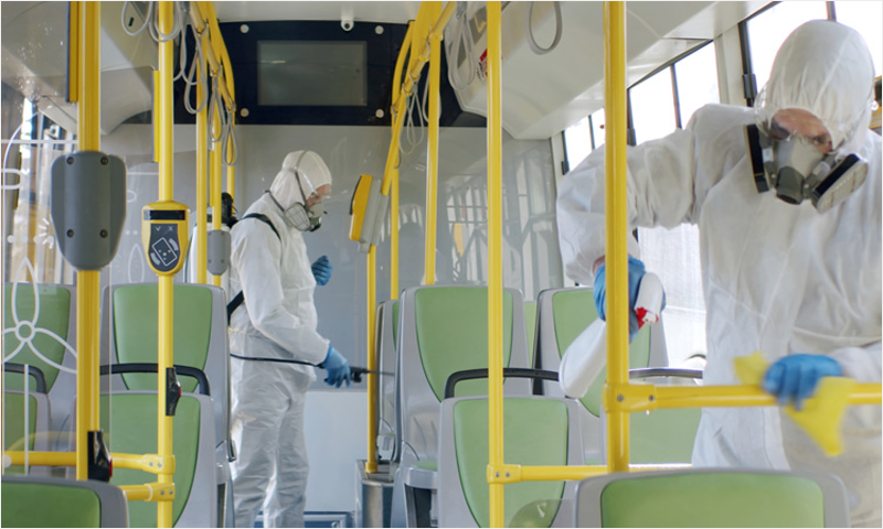 Dos personas con trajes especiales utilizando Resysten de Biovalia para desinfectar un autobús.