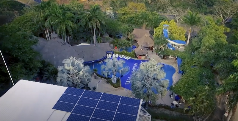 Placas solares colocadas en uno de los edificios del Hotel Villamartha, piscina con el nombre del hotel, imagen aérea.