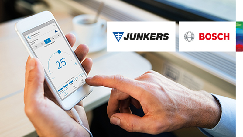 Una mano de hombre sostiene el móvil y con la otra navega por la aplicación homecom easy de Junkers Bosch.