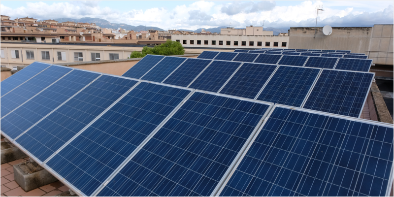 Placas solares instaladas y al fondo edificios.