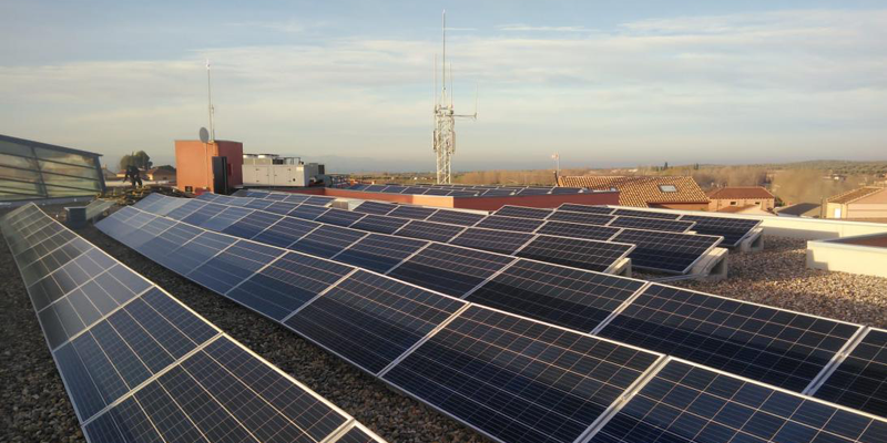 Placas solares instaladas en el tejado de un edificio y al fondo tejados de otras viviendas.