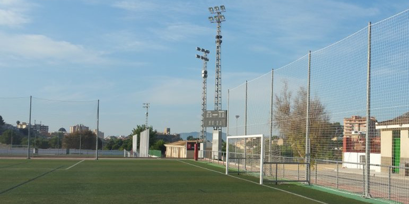 Campo de fútbol, portería y proyectores de iluminación artificial.