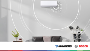 Un salón en el que hay un sofá y en la pared un aparato de aire acondicionado.