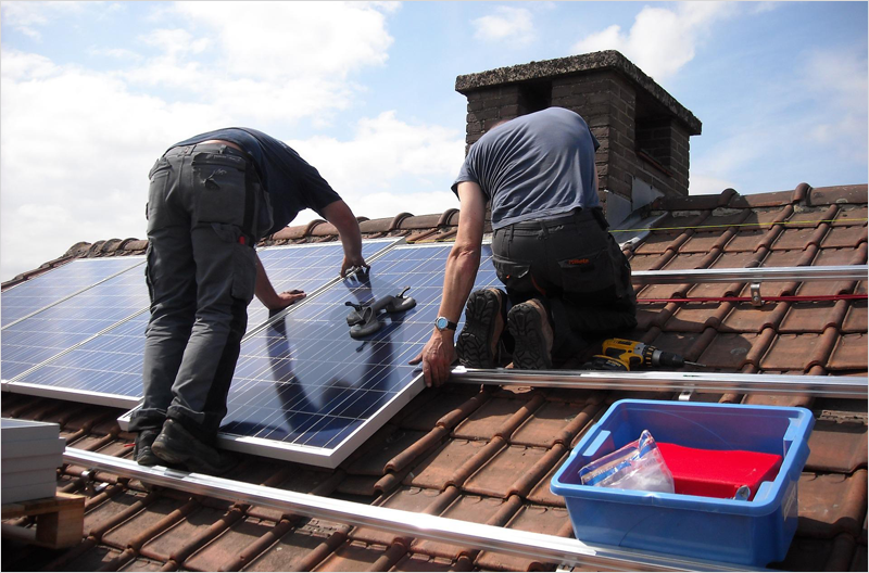 Dos instaladores colocando placas solares en un tejado.