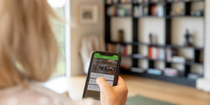 Mujer de espaldas en un salón y con un móvil respondiendo una encuesta.