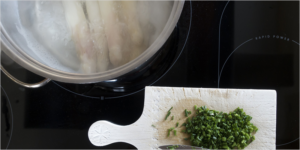 Vitrocerámica con una olla y una mesa de cortar con pimiento.