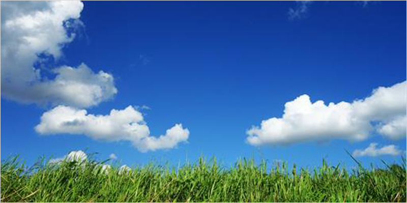 Cesped verde y cielo azul con nubes blancas simulando aire limpio.