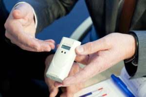 Dos manos de un hombre sujetan un repartidor de costes de ISTA.