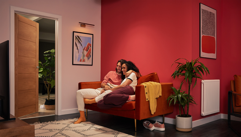 Salón de una vivienda y una pareja abrazada en el sofá viendo la televisión.