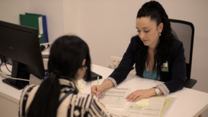 Chica asesorando a otra mujer con una factura.