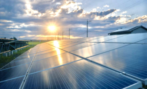 Sol ocultándose al atardecer y en primer plano una instalación de placas solares.