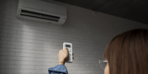 Chica con un mando apuntando a la bomba de calor.