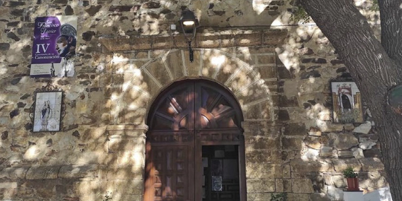 Puerta de madera de una iglesia abierta y una farola encima.