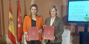 Dos mujeres posando con una carpeta cada una en las que están los papeles del acuerdo que han firmado.