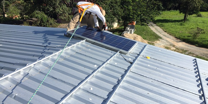 Operario instalando una placa solar en un tejado vacío.