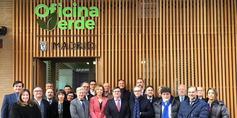 Hombres y mujeres sonriendo delante de la puerta de la Oficina Verde del Ayuntamiento de Madrid.