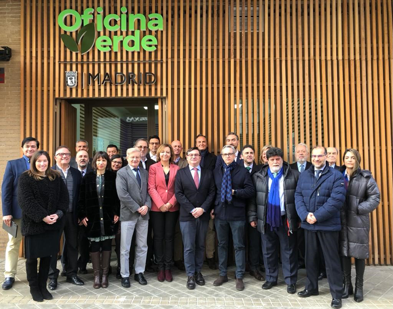 Hombres y mujeres sonriendo delante de la puerta de la Oficina Verde del Ayuntamiento de Madrid.