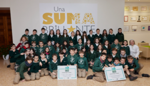 Alumnos de un colegio con uniforme posando con dos diplomas.