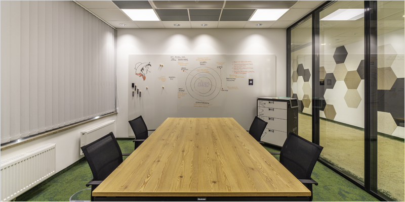 Sala de oficina con una mesa alargada rectangular y sillas alrededor e iluminada con buena luz.