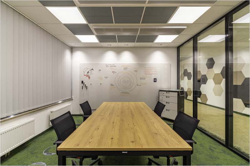 Sala de oficina con una mesa alargada rectangular y sillas alrededor e iluminada con buena luz.