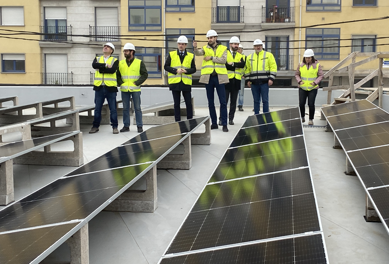 Varias personas con casco visitando unas instalaciones de placas solares en un tejado.