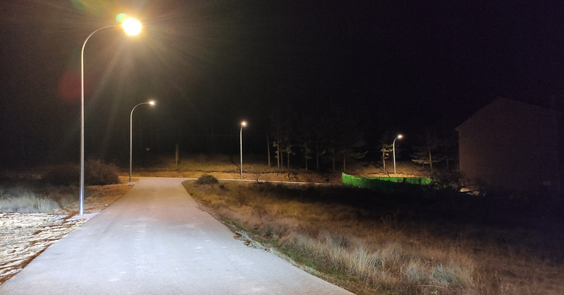 Farolas encendidas iluminando de noche una carretera secundaria.