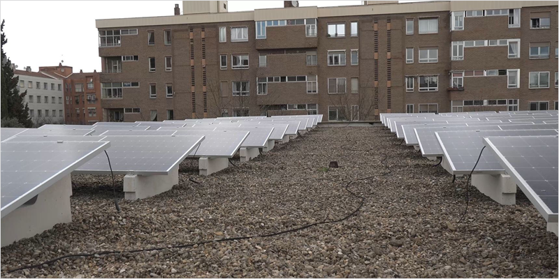 Placas solares instaladas en la azotea de un edificio y al fondo otro edificio de viviendas.