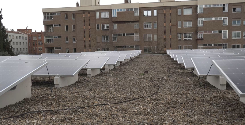 Placas solares instaladas en la azotea de un edificio y al fondo otro edificio de viviendas.