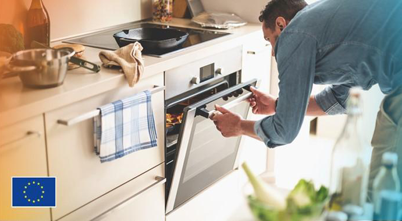 Hombre cerrando la puerta del horno y comida dentro cocinándose.