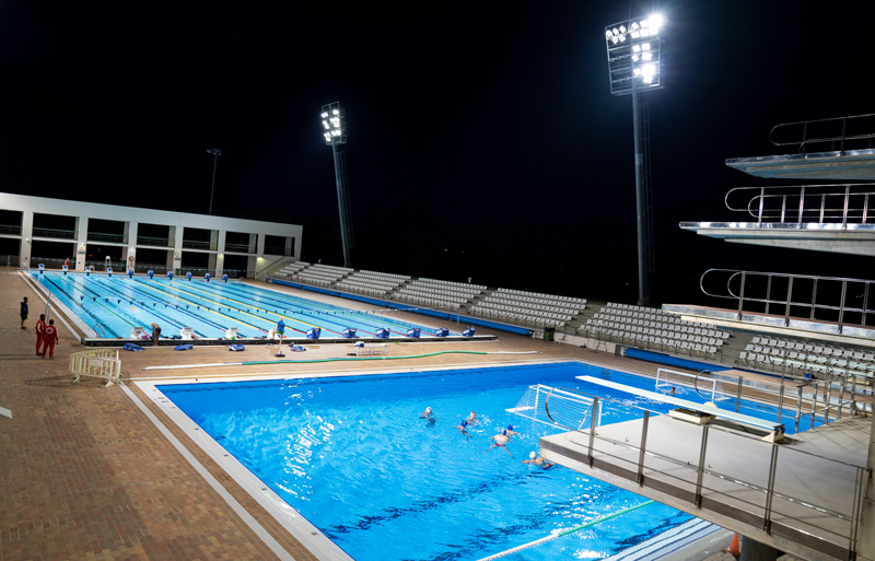 Dos piscinas al aire libre con focos iluminándolas de noche.