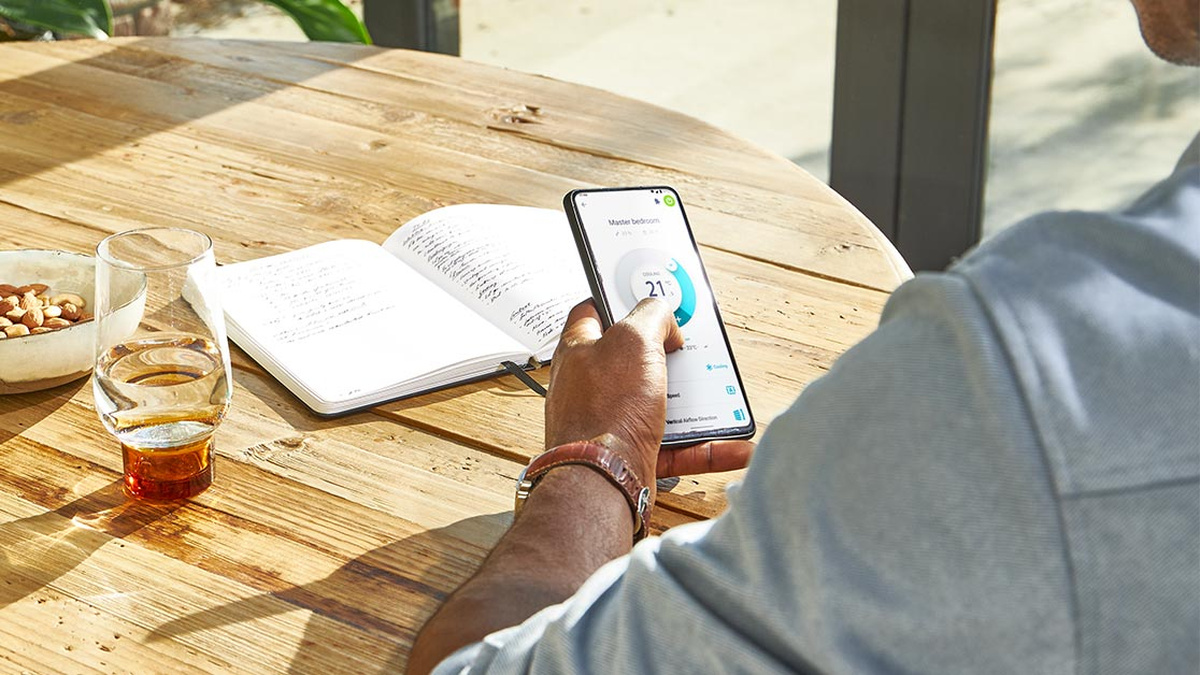 Persona utilizando la aplicación Daikin Onecta en un teléfono móvil para ajustar la climatización del hogar.